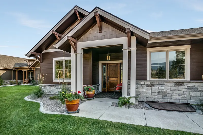 Front entrance landscaping with stone siding and concrete walkway.