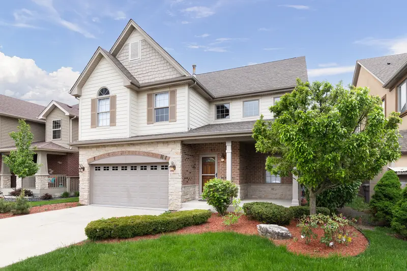 Front yard landscaping with mulch, shrubs, and a green lawn in front of a house.