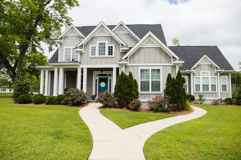 Front yard landscaping with a concrete walkway and manicured lawn.