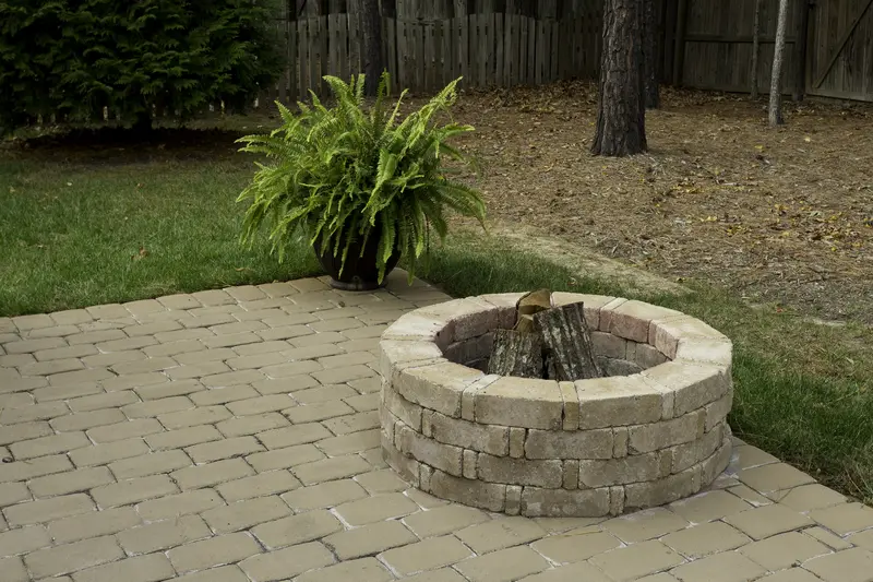 Custom brick fire pit on a professionally installed paver patio in backyard.